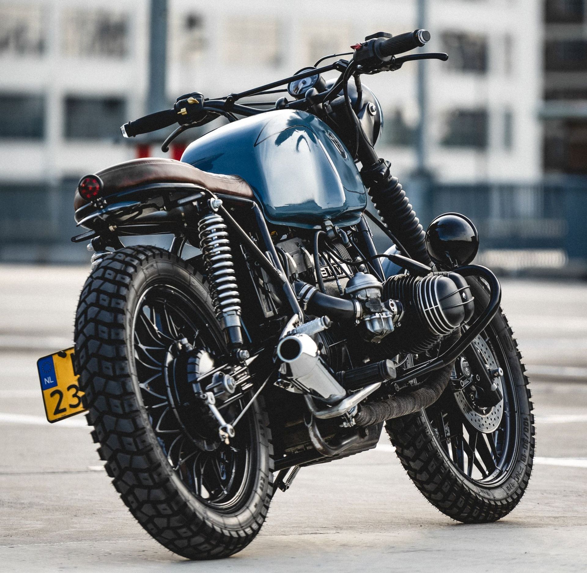 Blue and black custom motorcycle with knobby tires, outdoors.