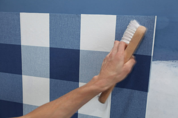 A person is painting a blue and white checkered wall with a brush