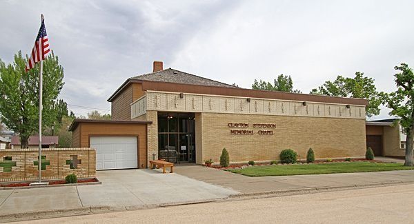 Brick community building with a white garage door, American flag, and trees on a cloudy day