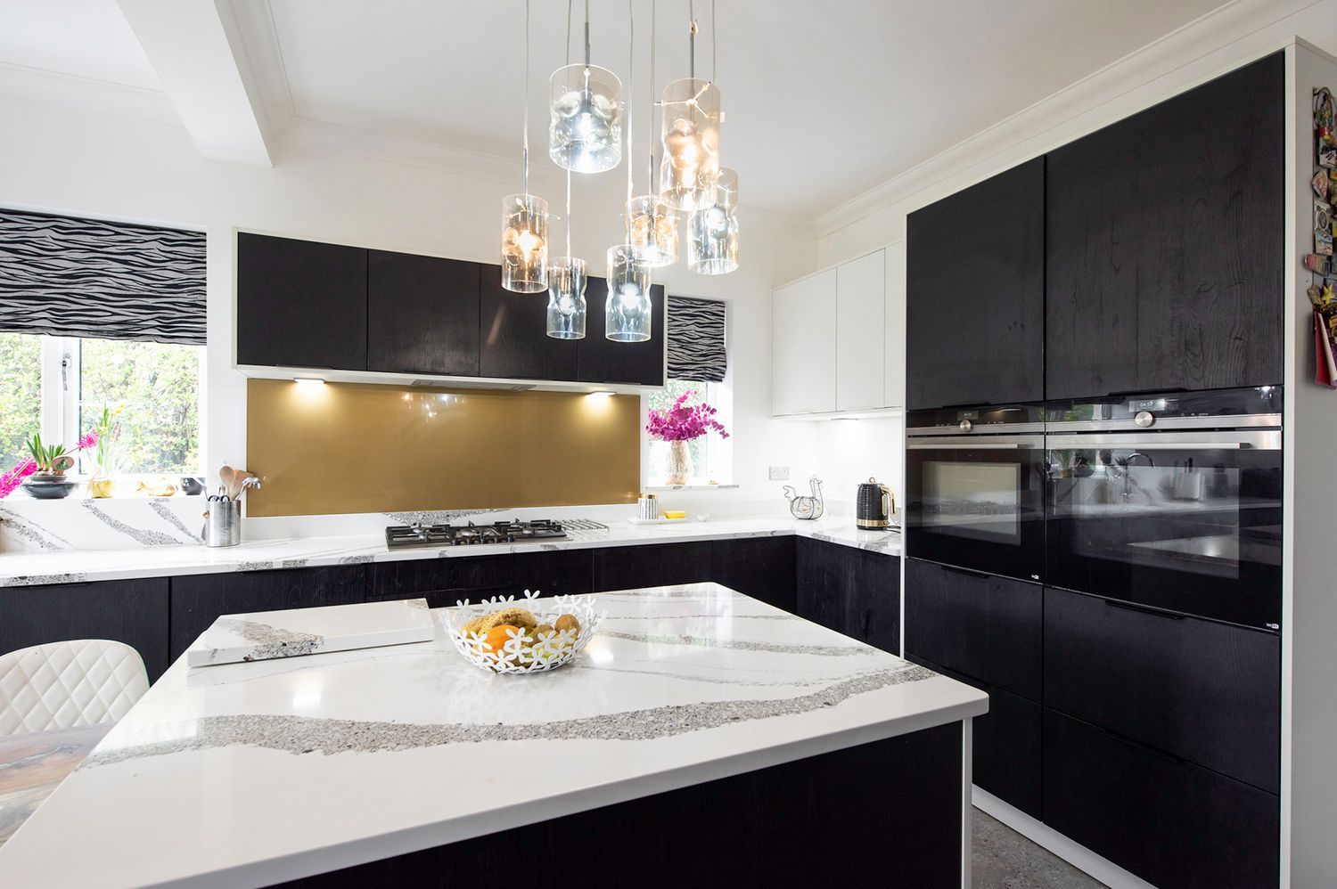 A kitchen with black and white cabinets and a large island in the middle.