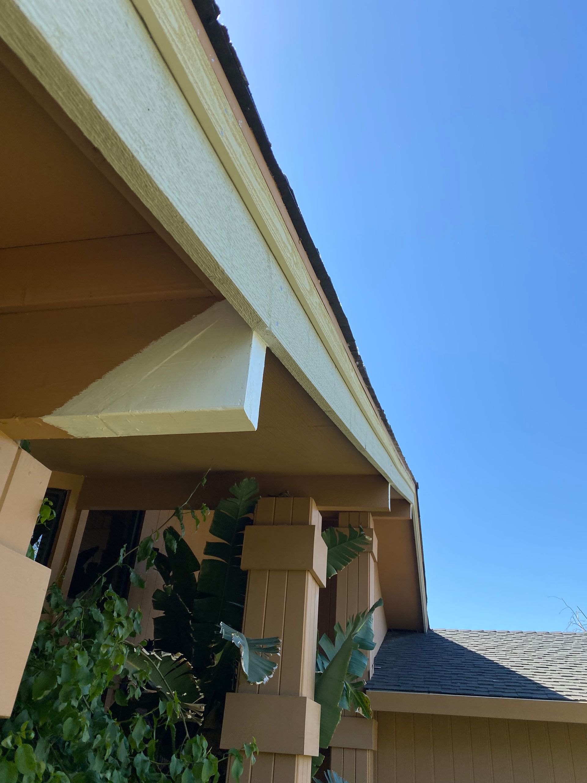 Close-up of a beige building roofline with decorative beams against a blue sky