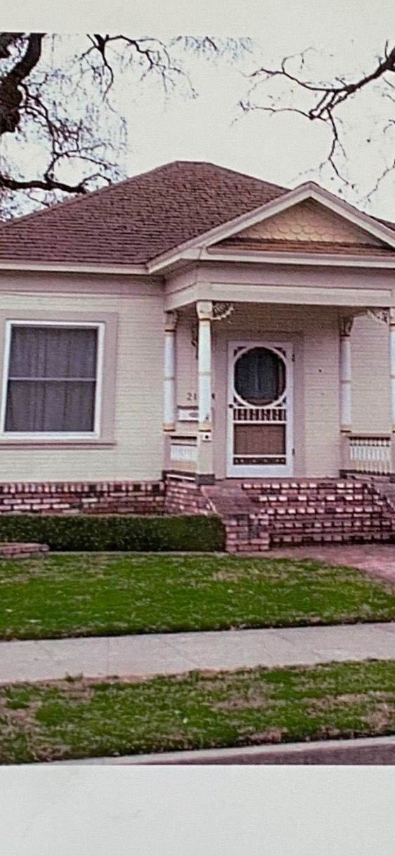 Small cream-colored house with brick steps, a front porch, and a large window