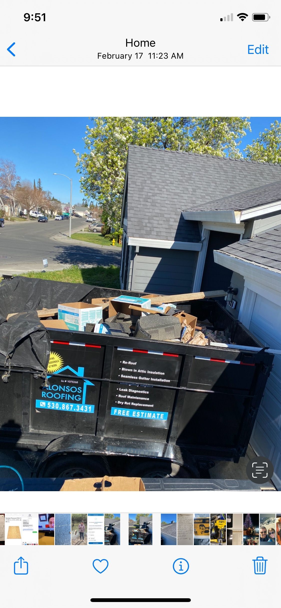 Trash and recycling bins piled with cardboard beside a house driveway on a sunny day