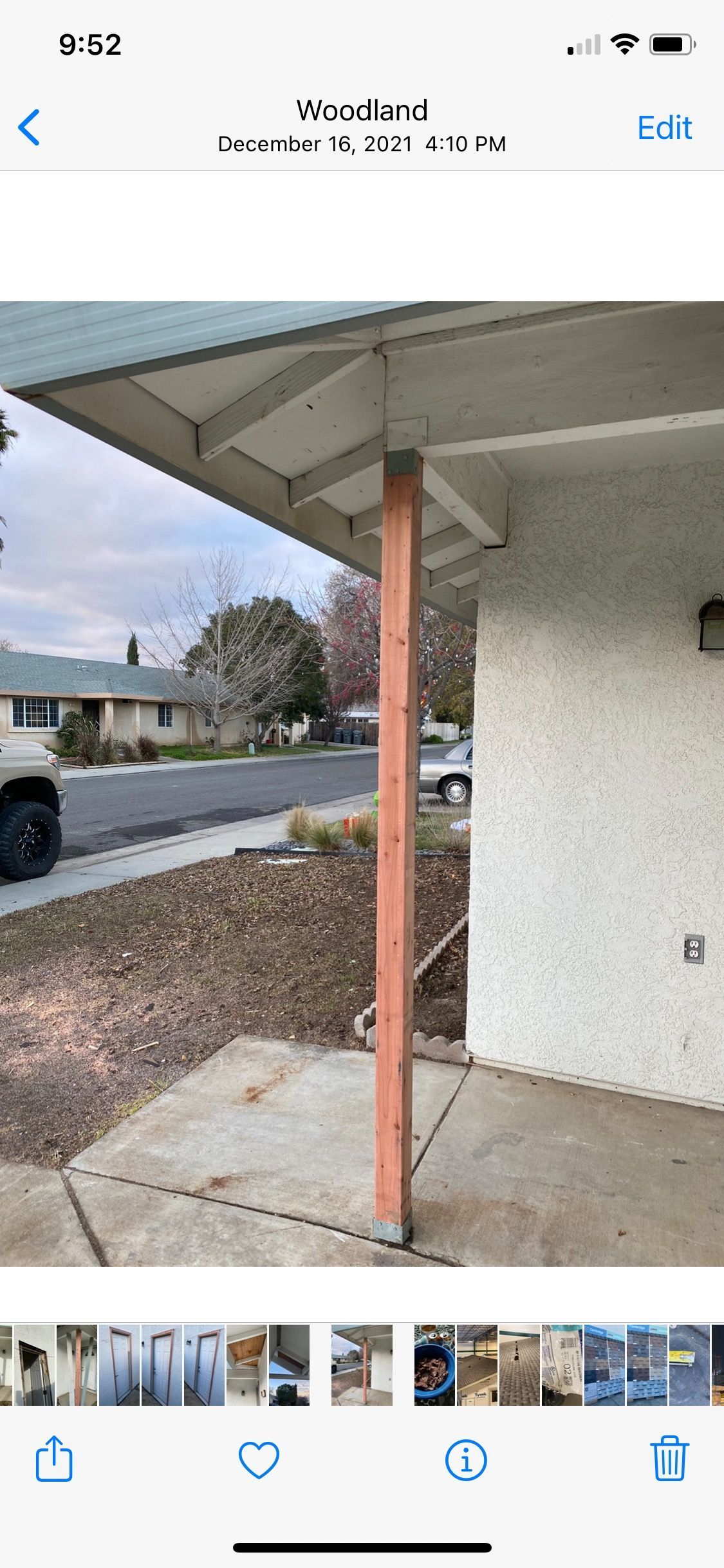 Front porch with a rust-colored support post under a roof overhang beside a stucco wall and driveway.
