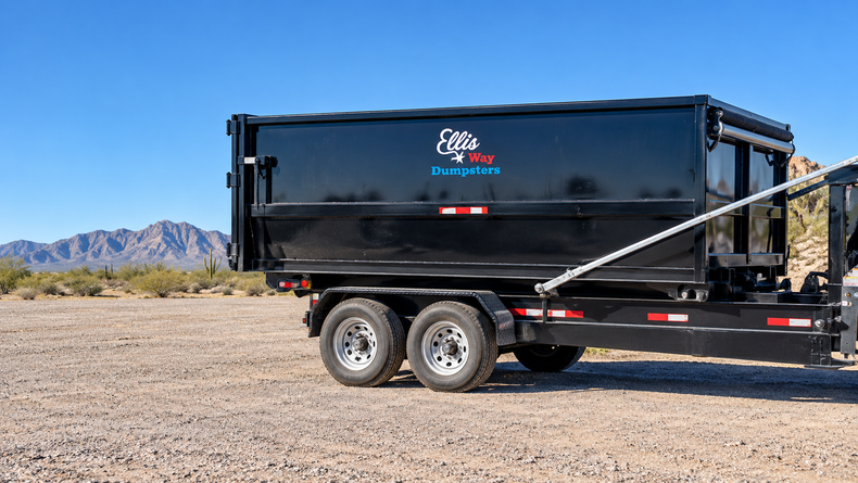 Black dump trailer parked on a gravel lot with mountains in the background