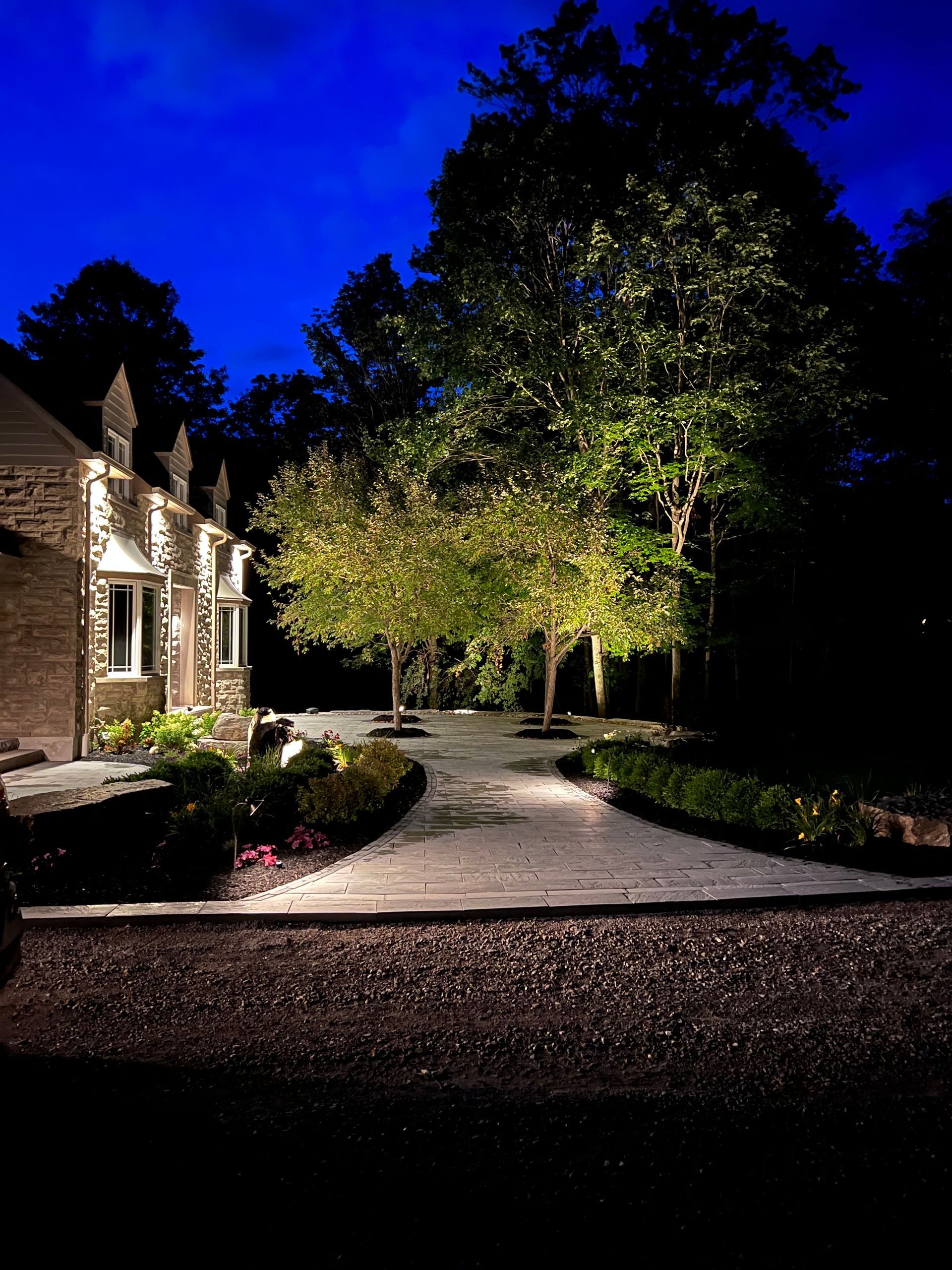 A driveway leading to a house is lit up at night