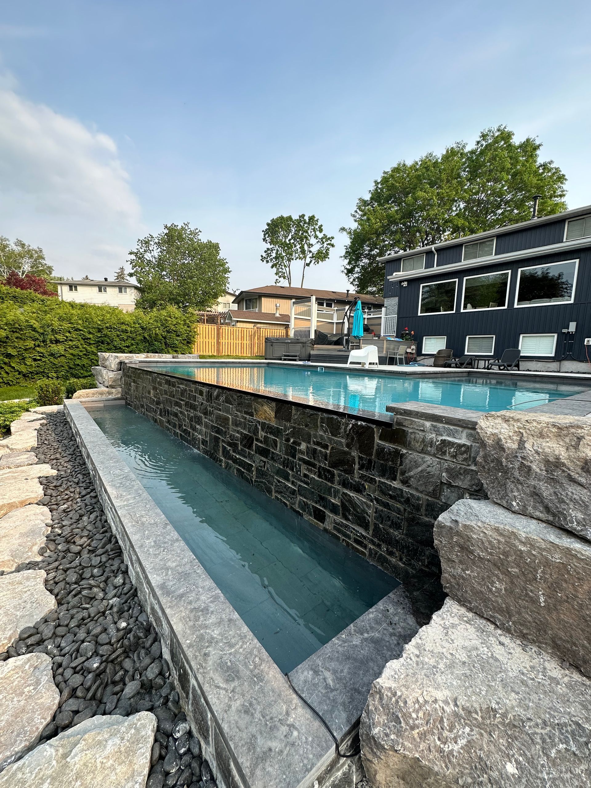 There is a large swimming pool in the backyard of a house.