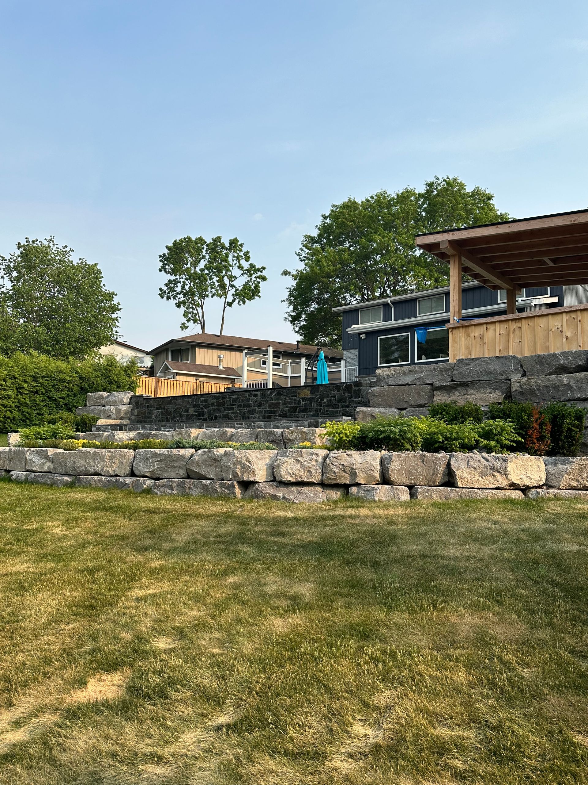 A house is sitting on top of a hill next to a large rock wall.