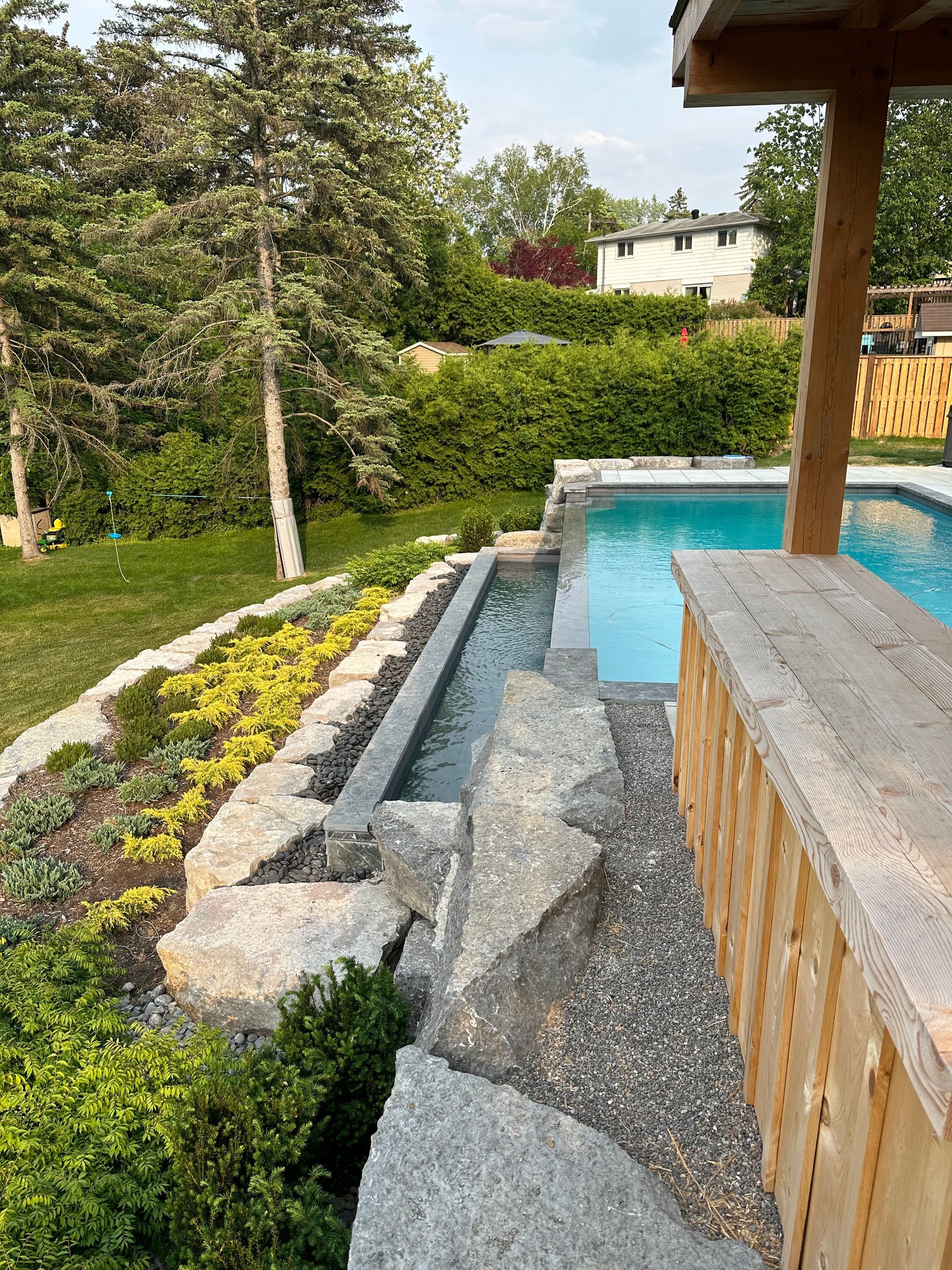 There is a swimming pool in the backyard with a wooden bar.