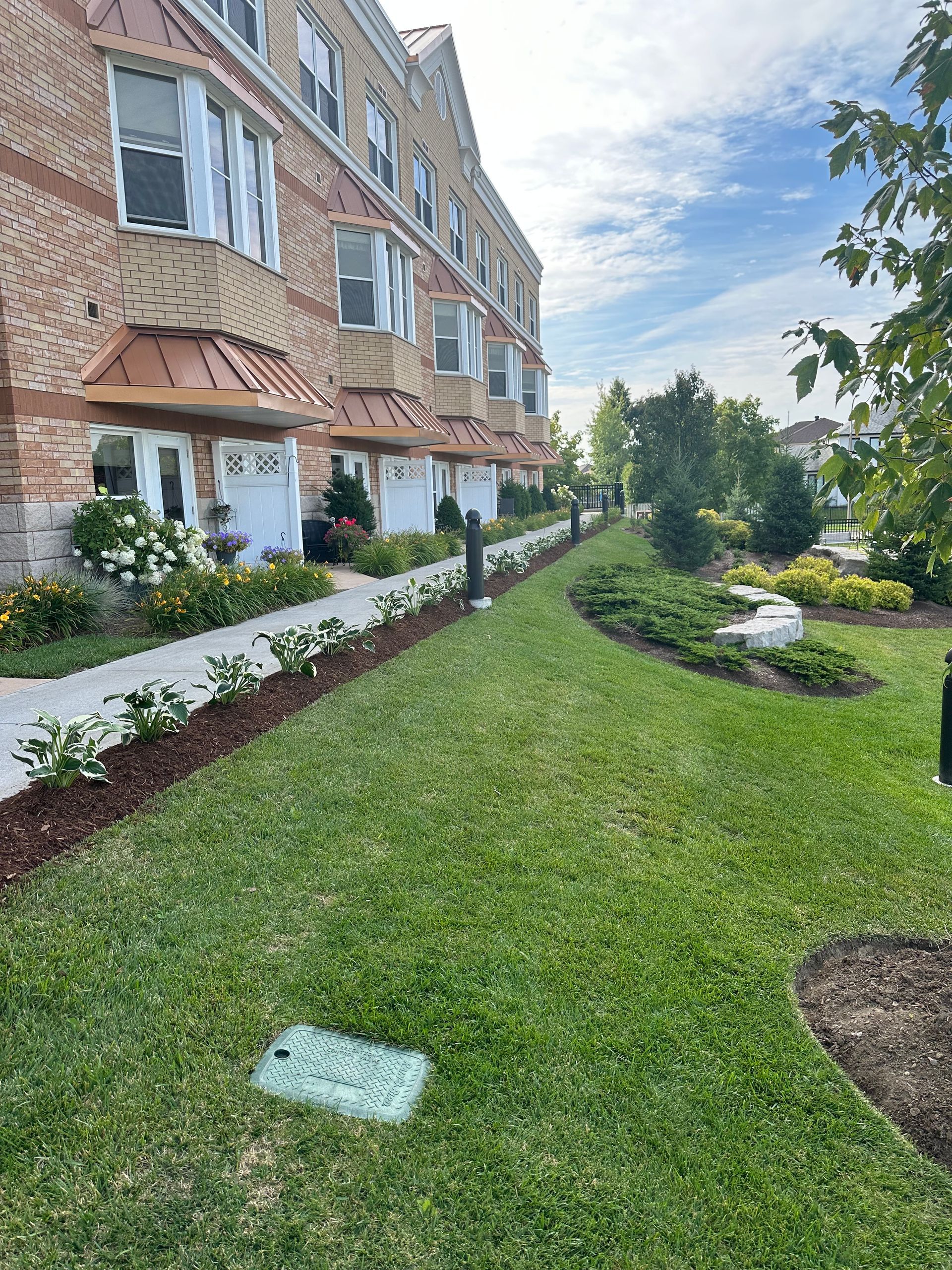 A row of apartment buildings with a lush green lawn in front of them.