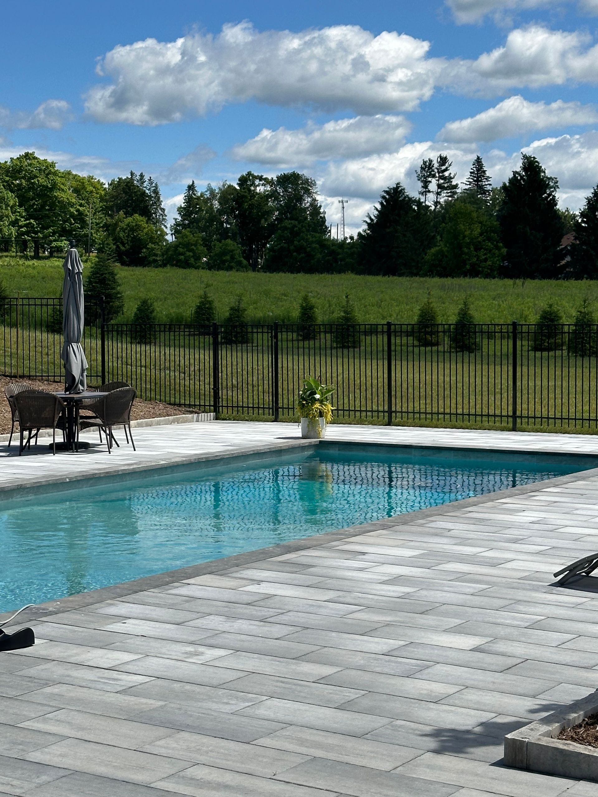 A large swimming pool is surrounded by a fence and chairs