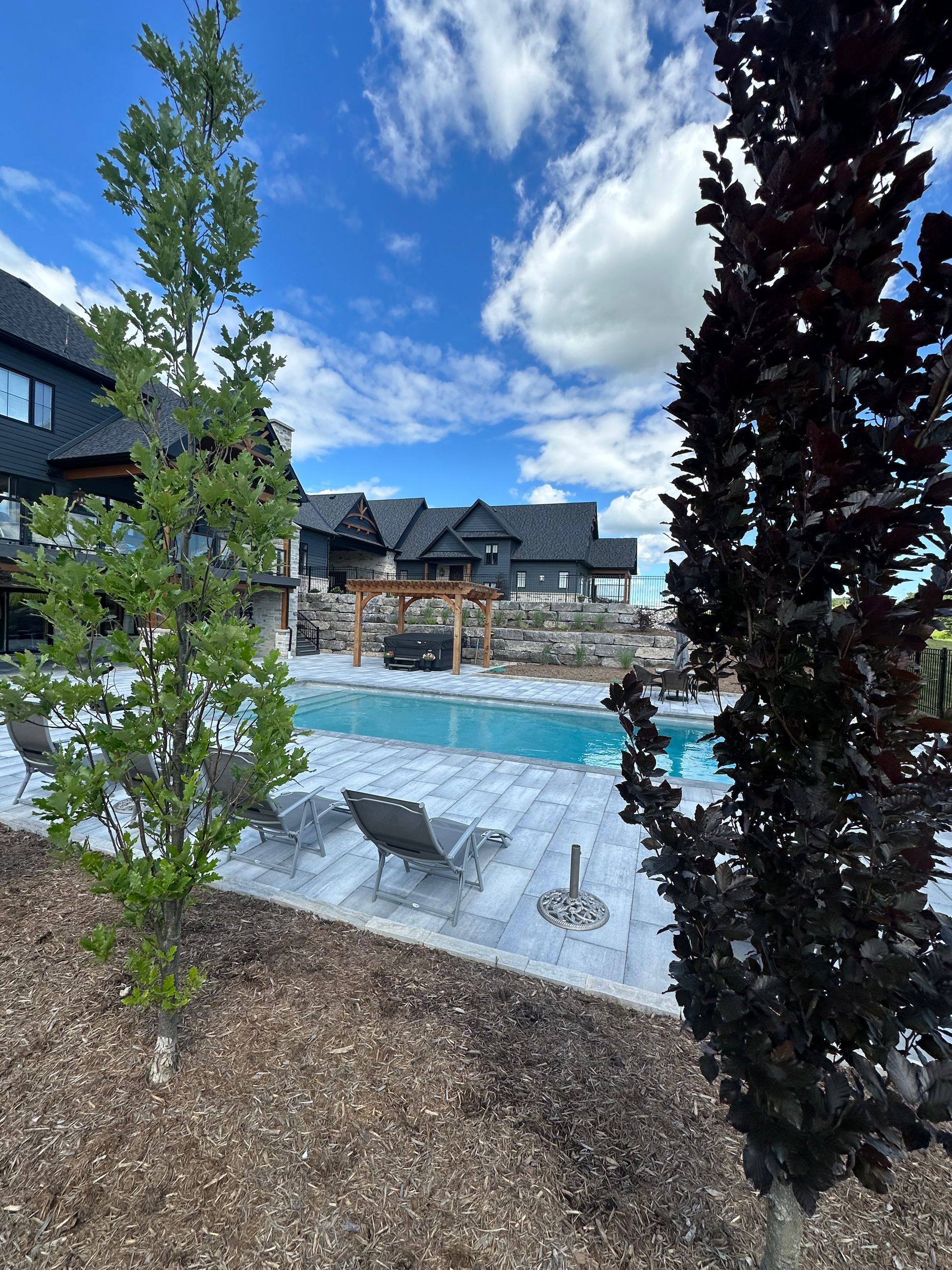 There is a large swimming pool in the backyard of a house.