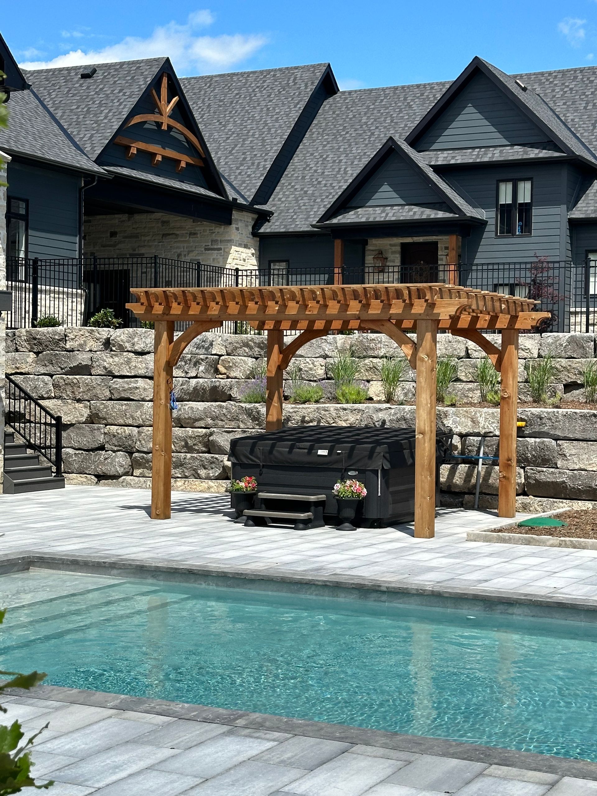 A large house with a pool and a pergola in front of it.