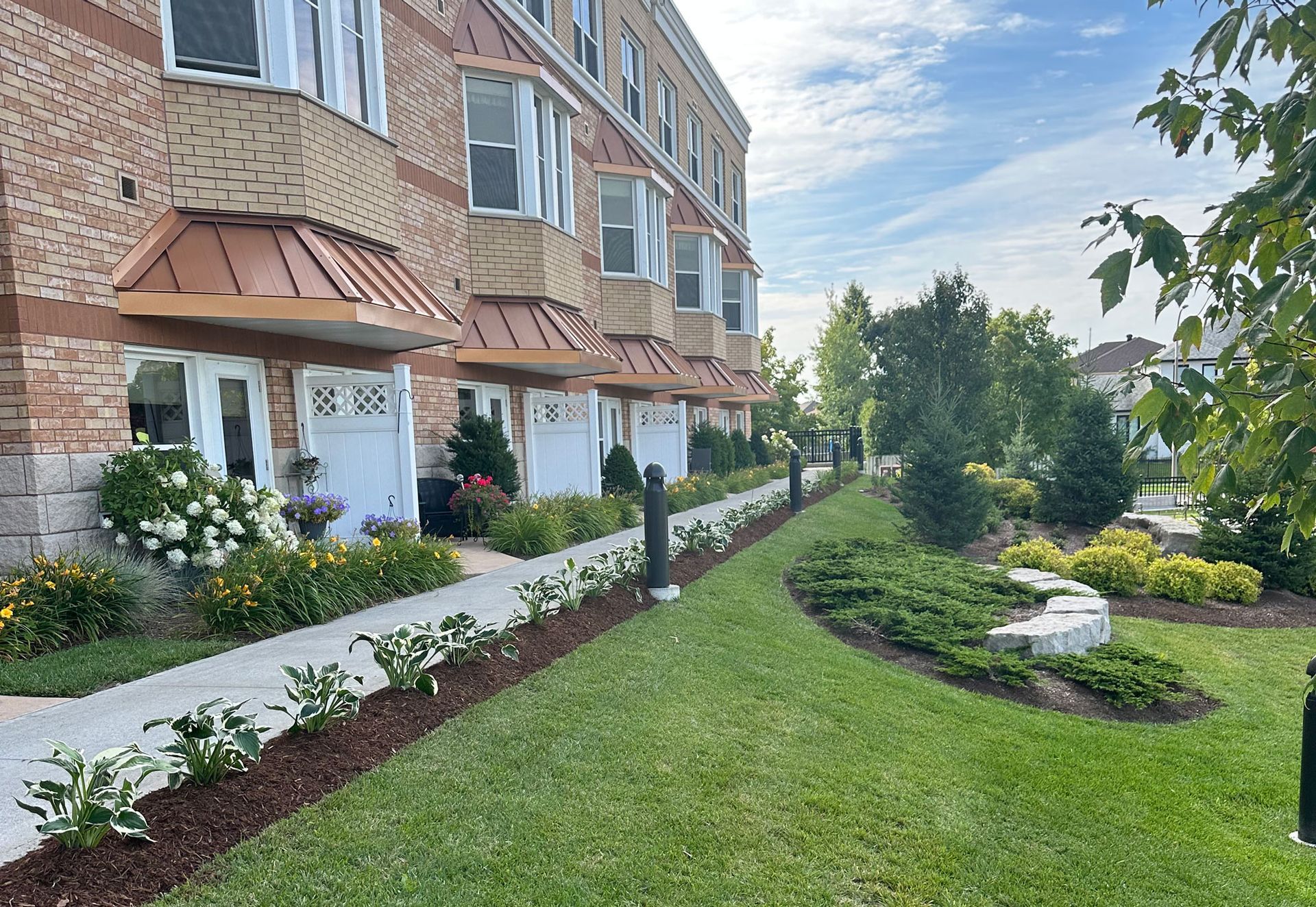 A brick apartment building with a lush green lawn in front of it.