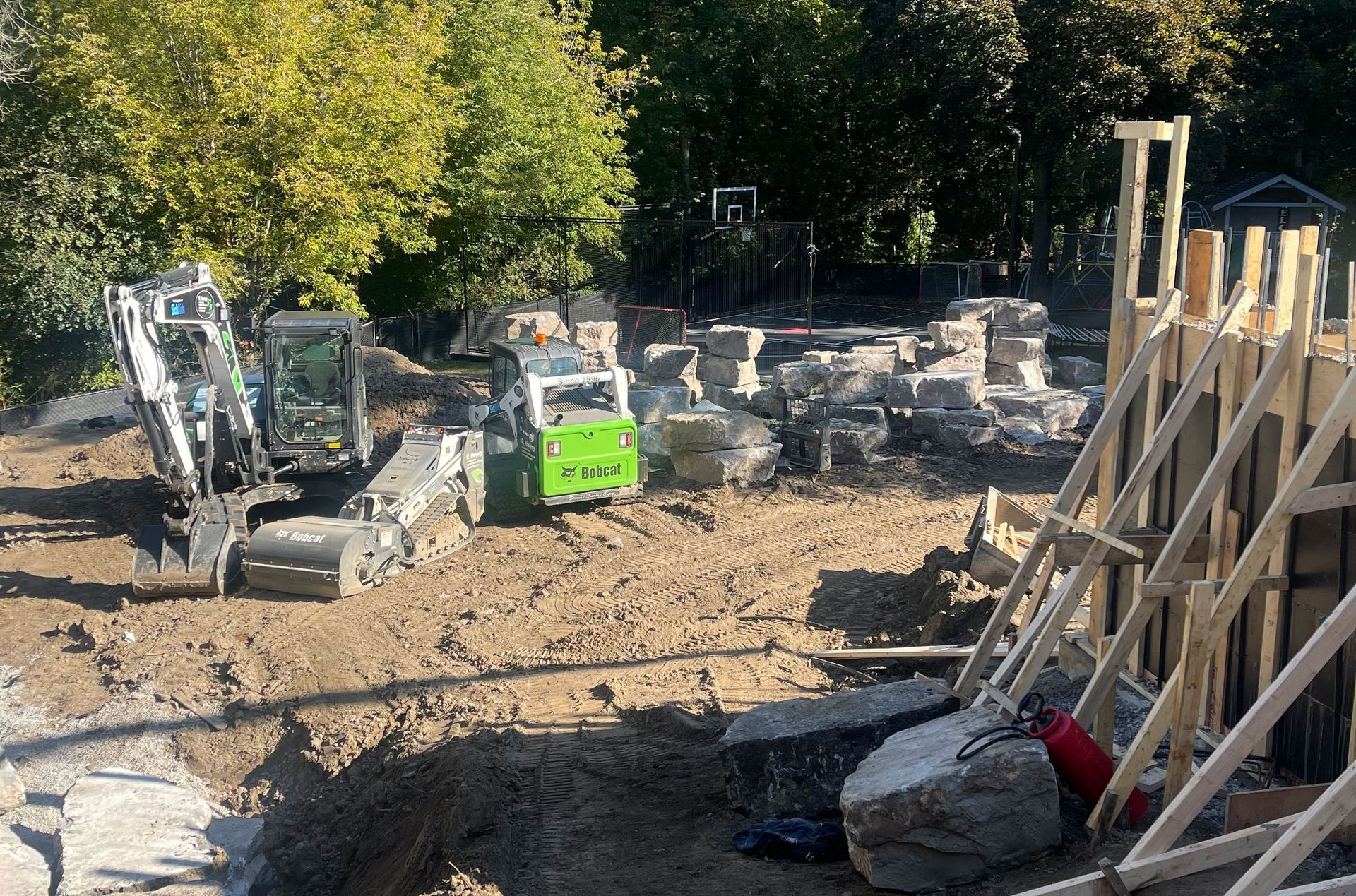 A construction site with a green excavator and a white excavator.