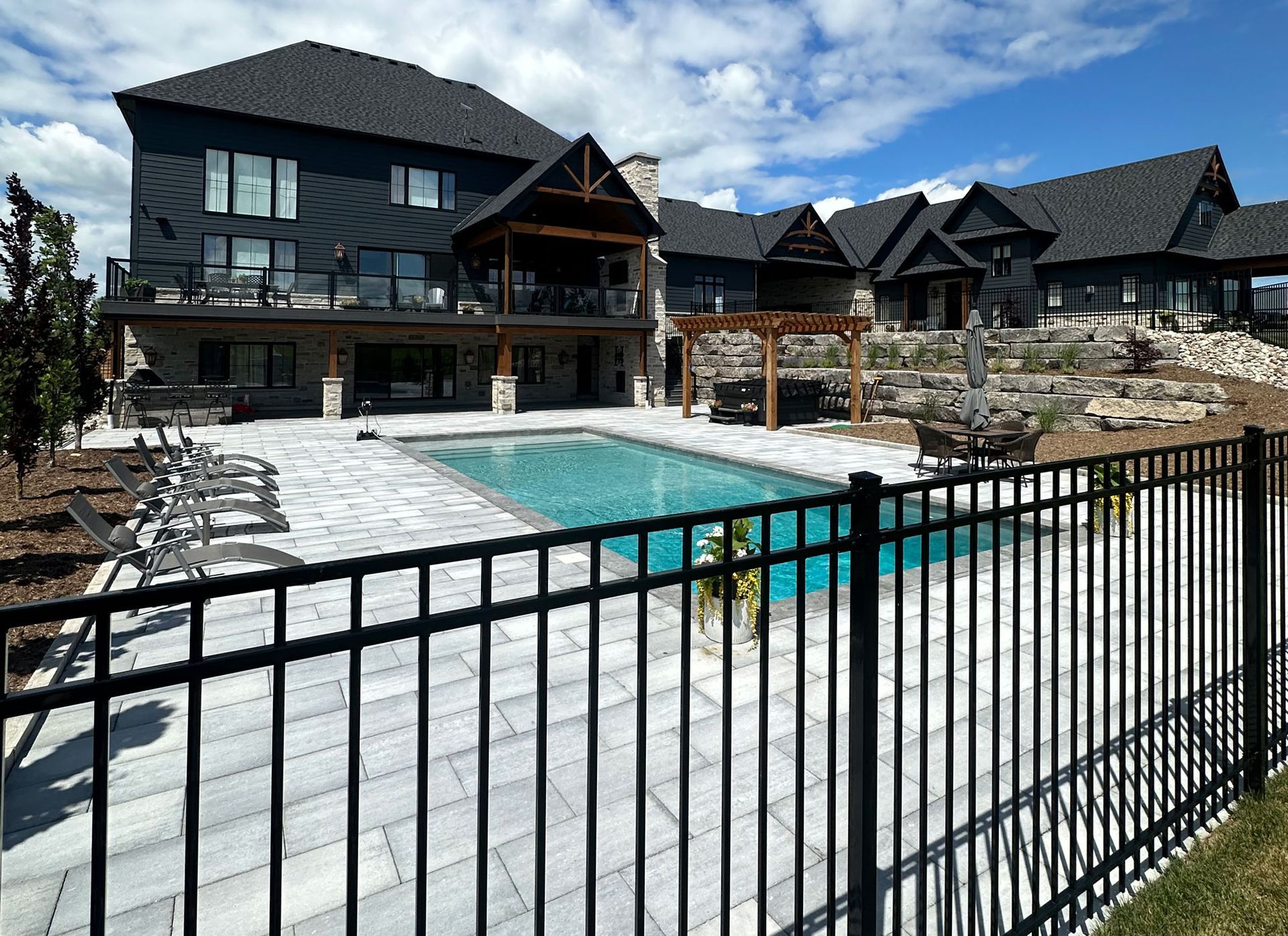 A large house with a swimming pool behind a metal fence.