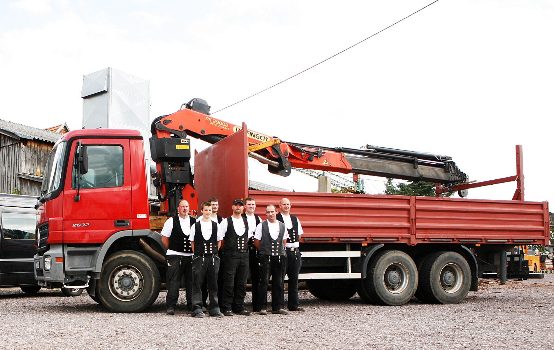 Mannschaft-/Gruppenbild Mitarbeiter vor rotem LKW mit Kran