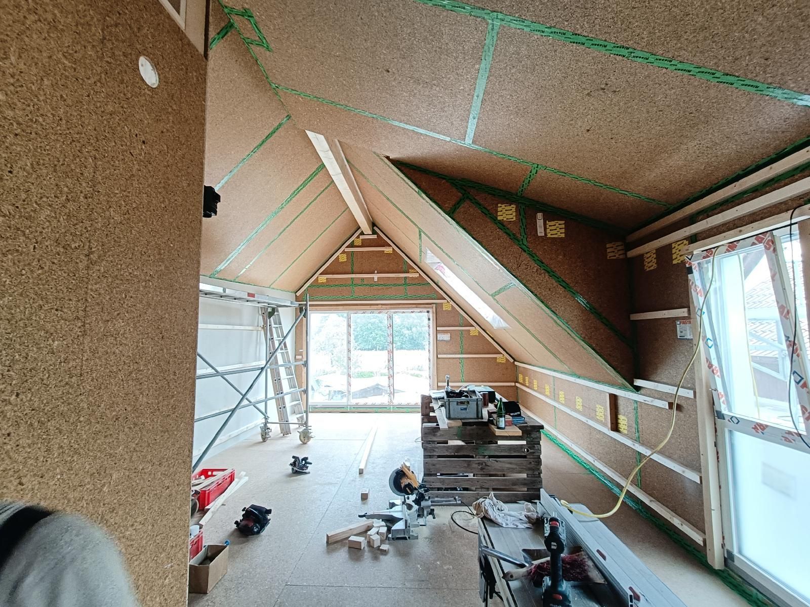 Das Innere eines neu gebauten Daches. In der Gaube ist eine dreiteilige Schiebetür aus Glas