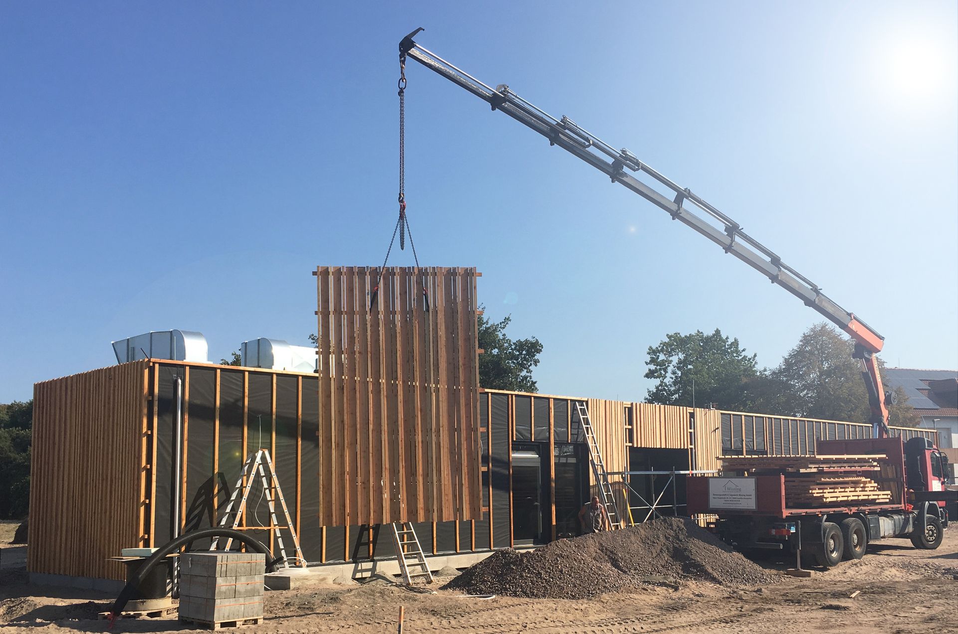 ein Teil der neuen Holzfassade wird mit einem Autokran an das Gebäude angebracht.