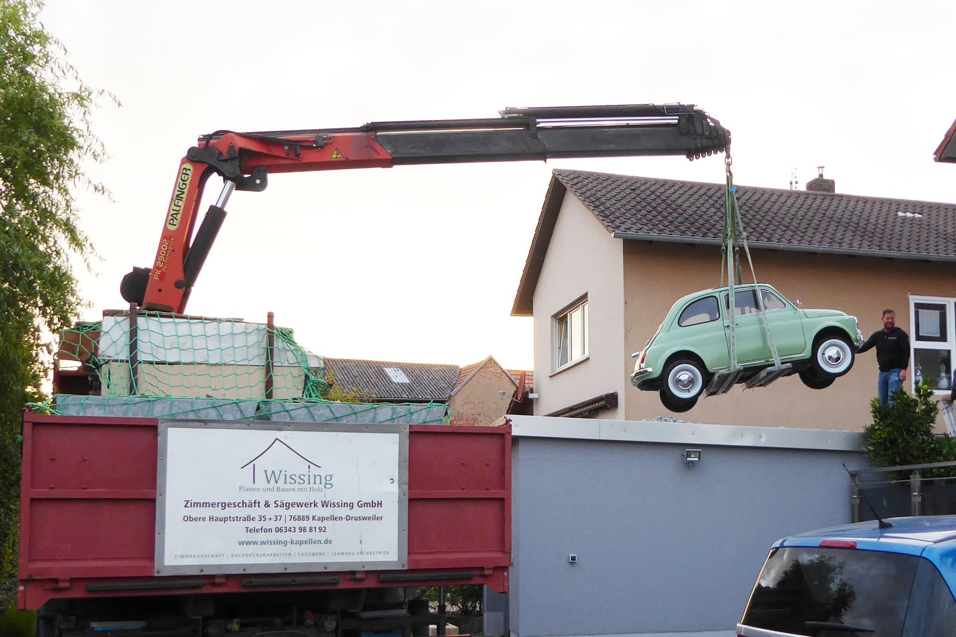 Ein Kran der Firma Wissing. Er hat einen kleinen Oldtimer geladen und bringt diesen gerade in Position