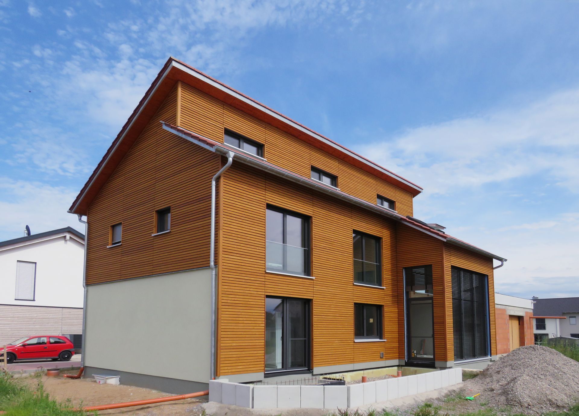 Einfamilienhaus mit schöner Holzfassade vor blauem Himmel