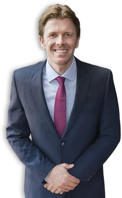 Smiling person in a navy suit with a magenta tie, standing against a white background.