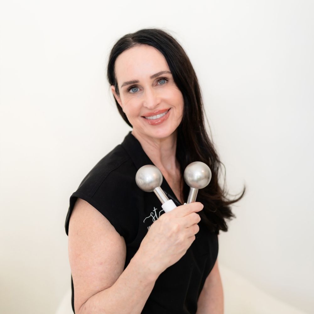 Portrait of Julie Diep, Licensed Clinical Aesthetician at Skin & Tonic, holding professional silver facial massage globes.