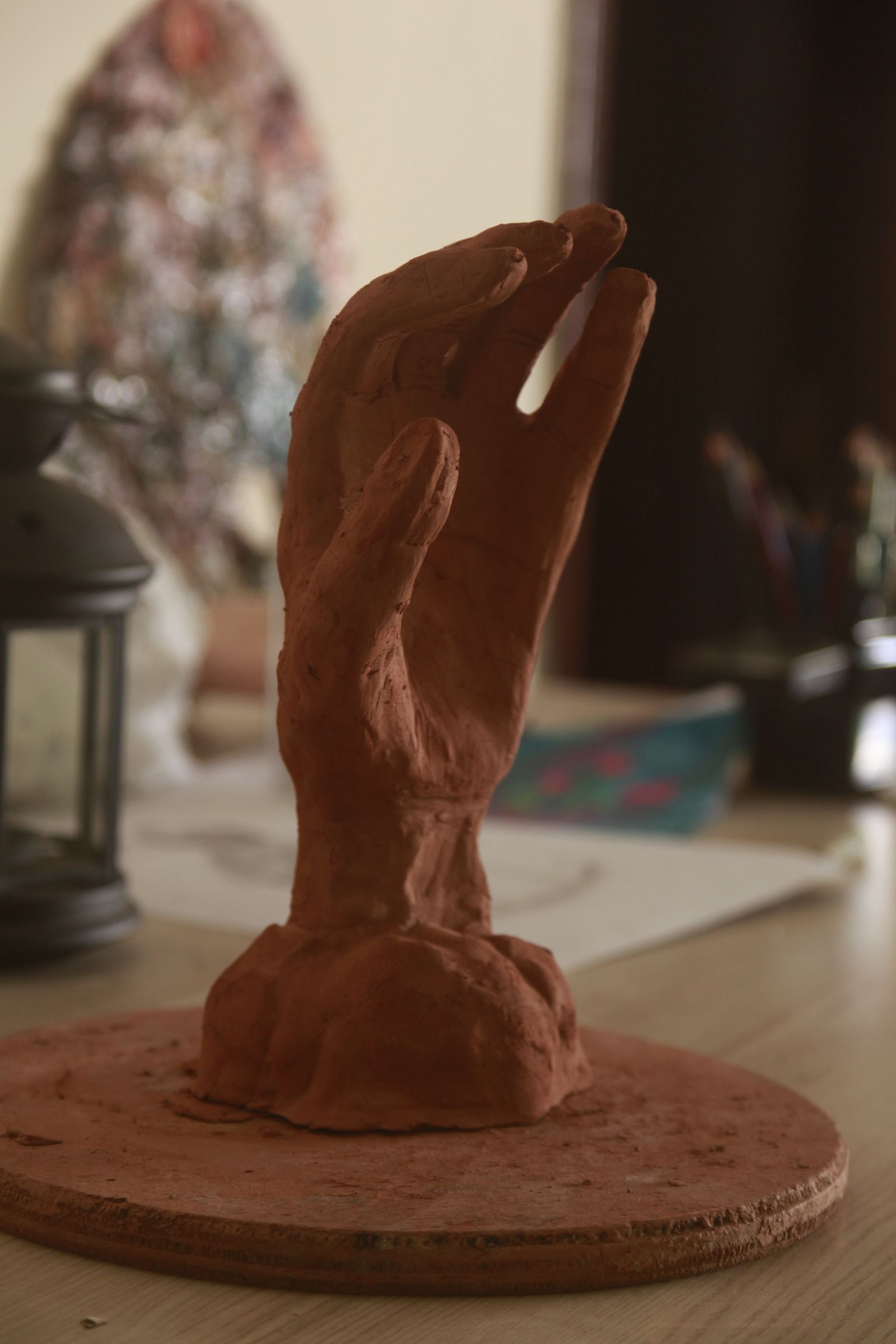 Hands shaping a column of soft terracotta clay