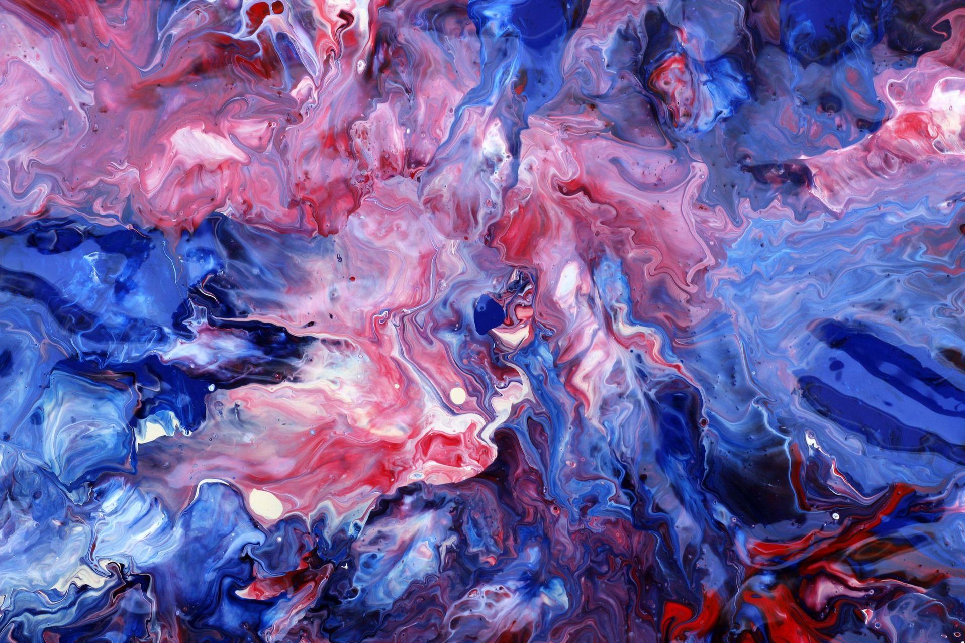 Crimson, white and deep blue acrylic pour spreading across a canvas