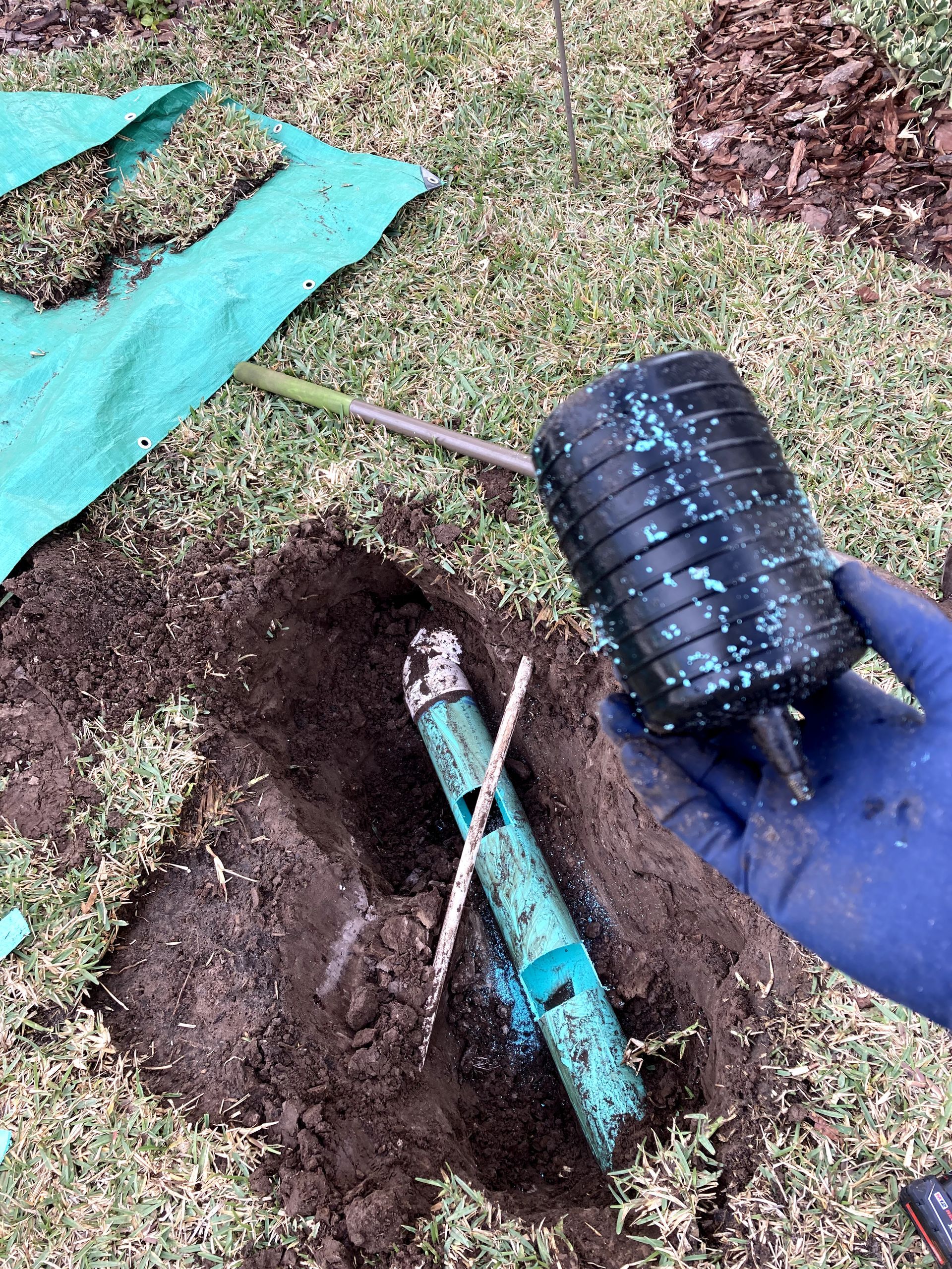 A person is digging a hole in the ground to fix a pipe.