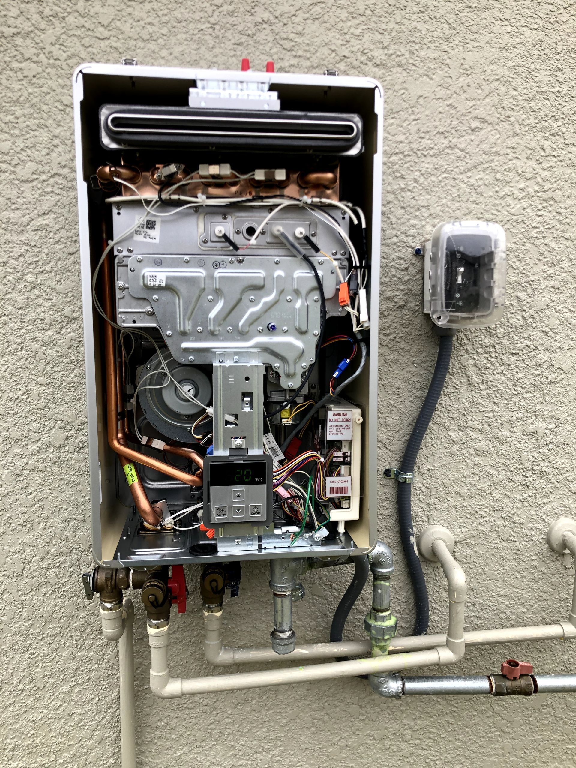 A water heater is sitting on the side of a building.