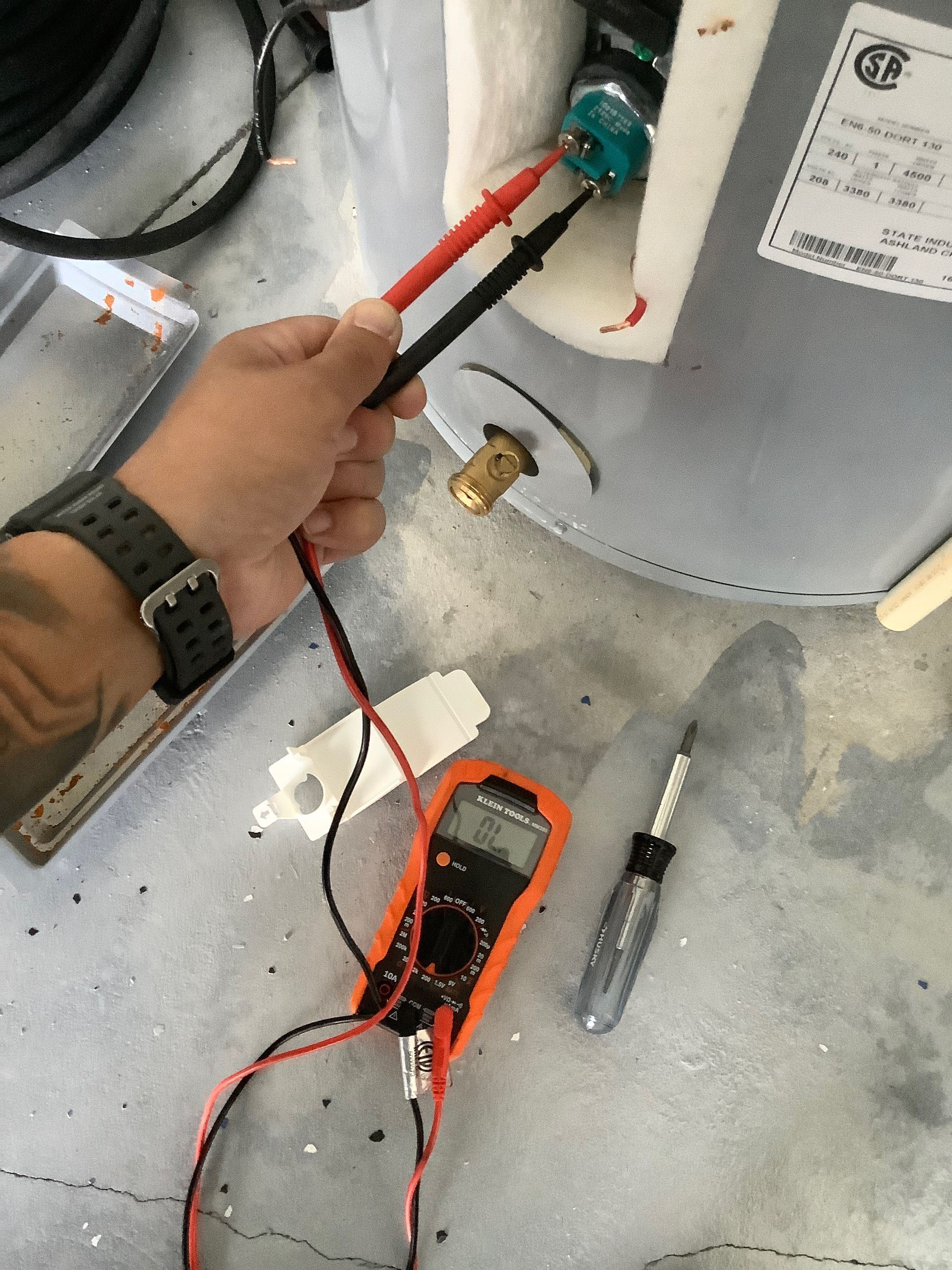A person is using a multimeter to test a water heater