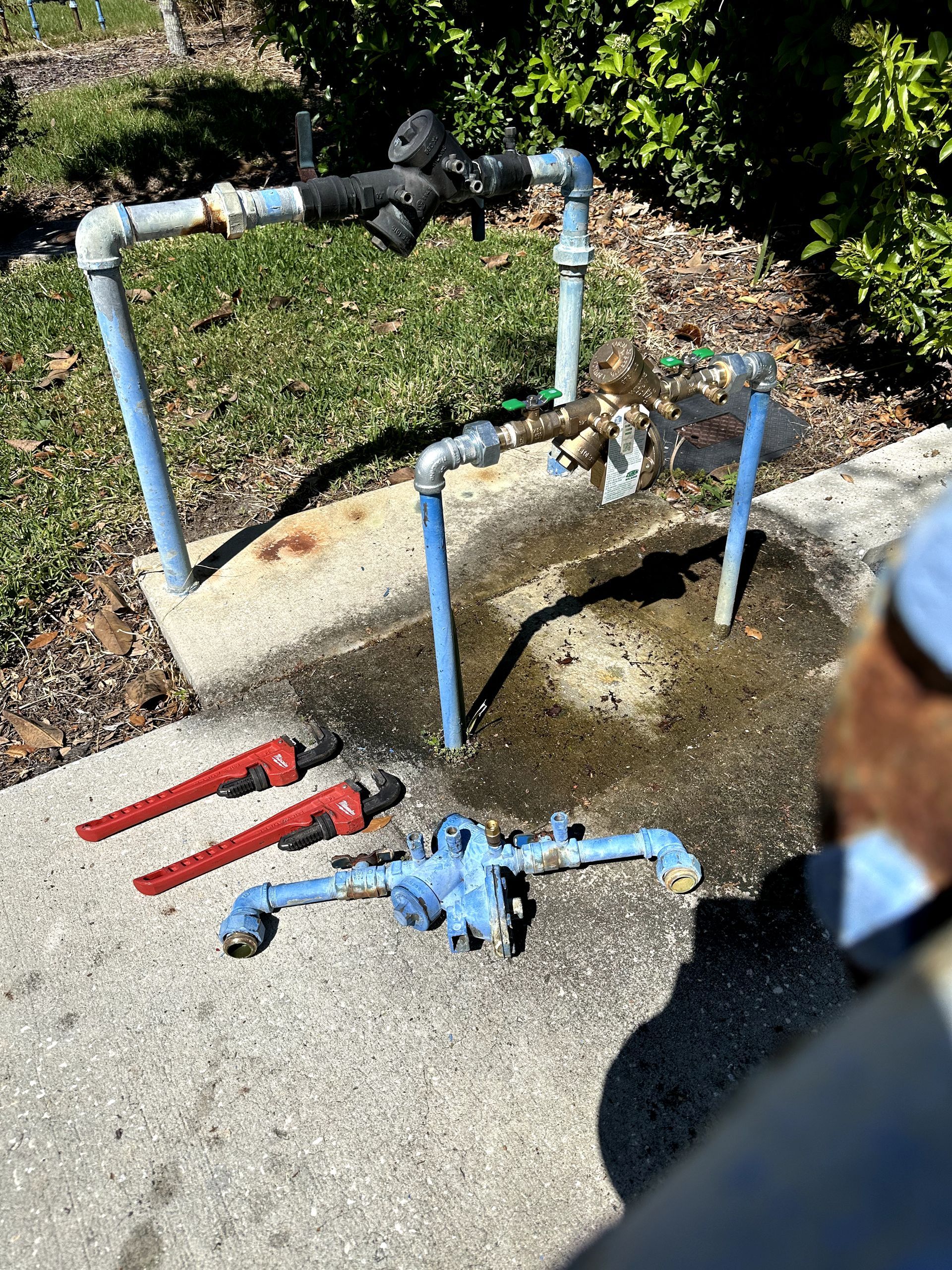 A man is standing next to a pipe with a wrench on it.