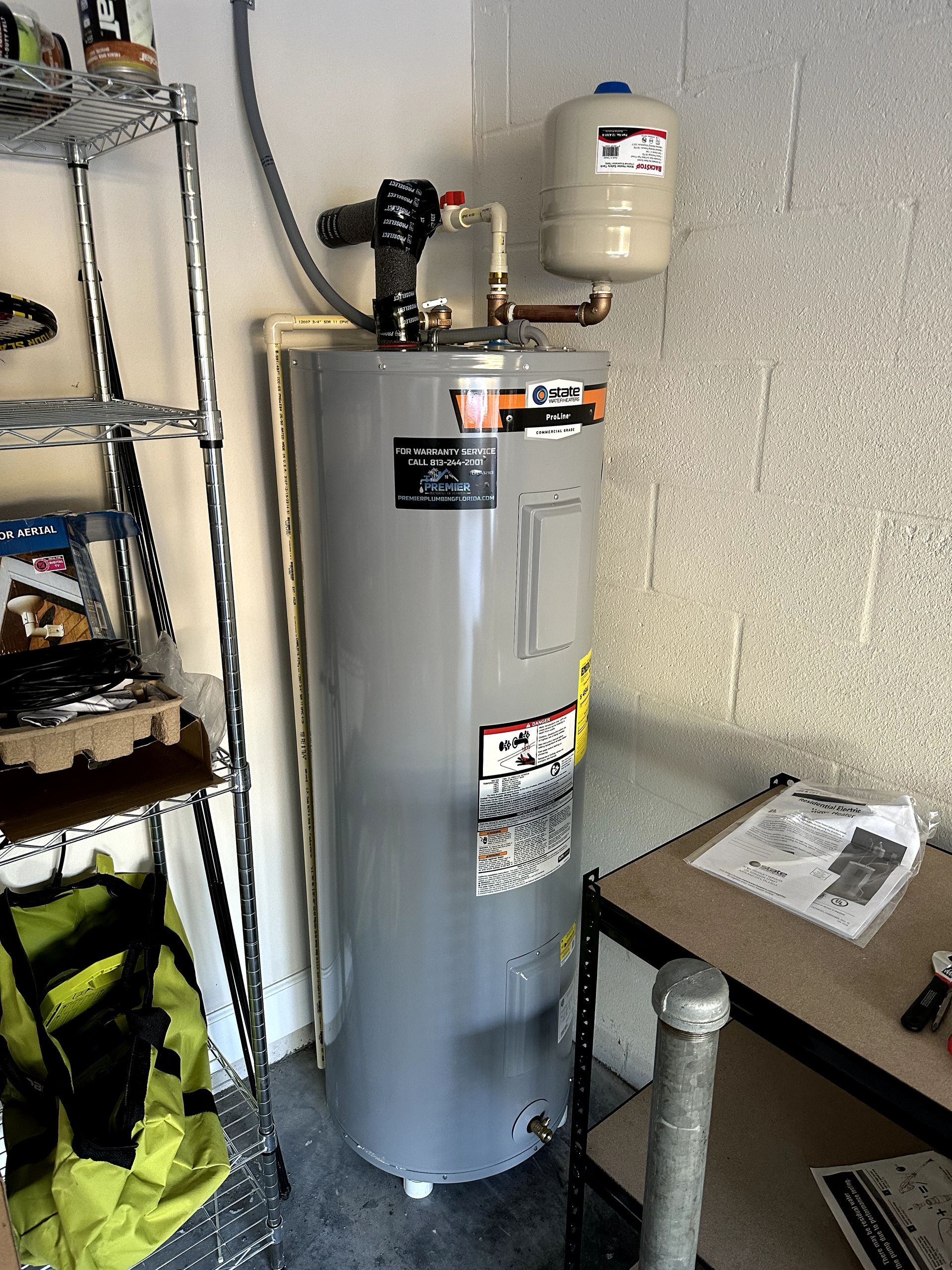 A water heater is sitting in a garage next to a table.