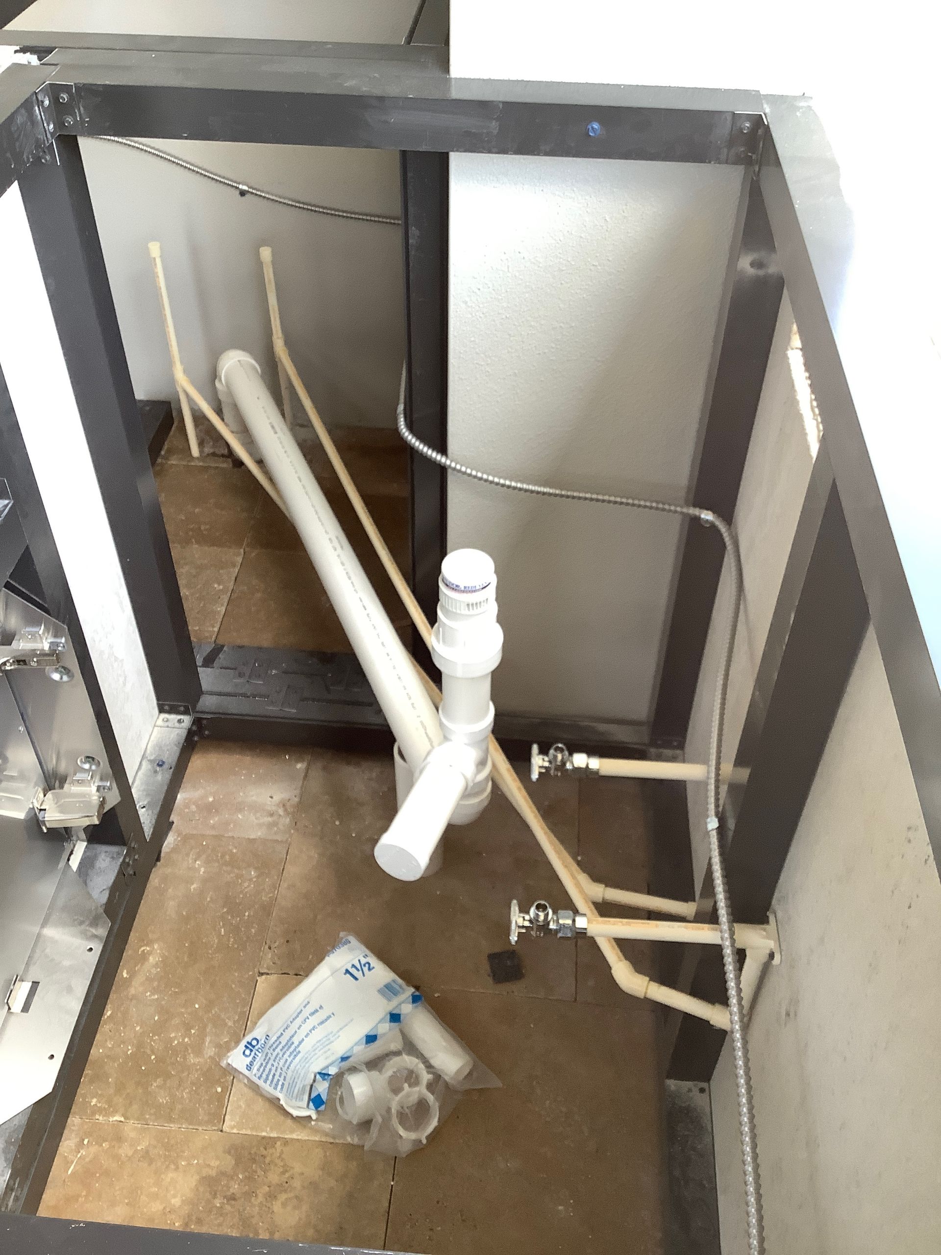 A white pipe is laying on the floor in a bathroom