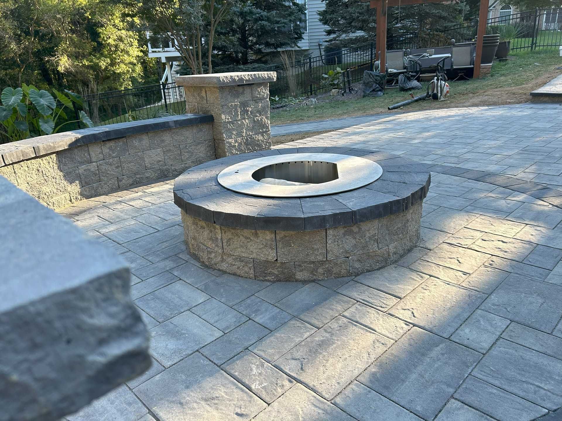 Fire pit made of brick with a silver top on a stone patio.