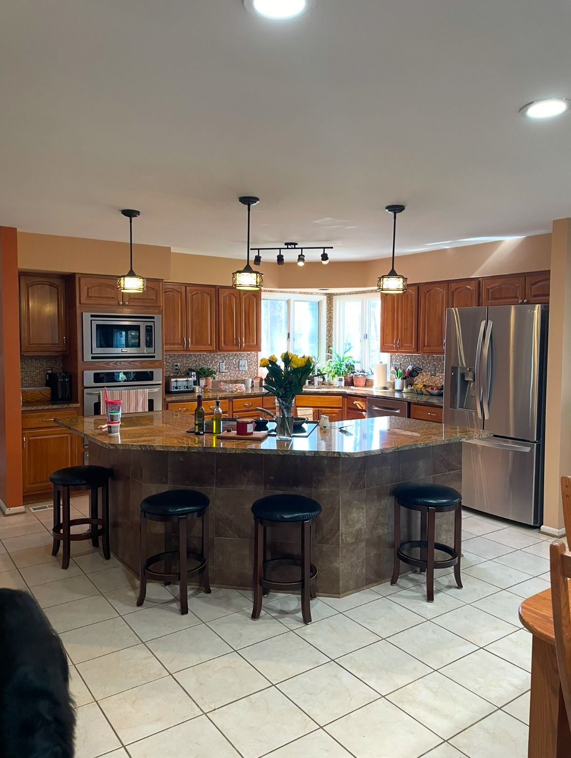 Kitchen with large island, wood cabinets, stainless steel appliances, and tile floor.