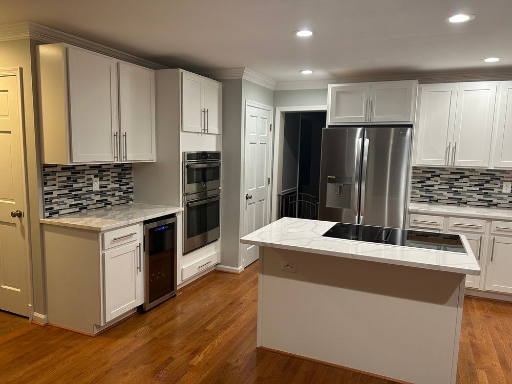 White kitchen with hardwood floors, white cabinets, stainless steel appliances, and a central island.