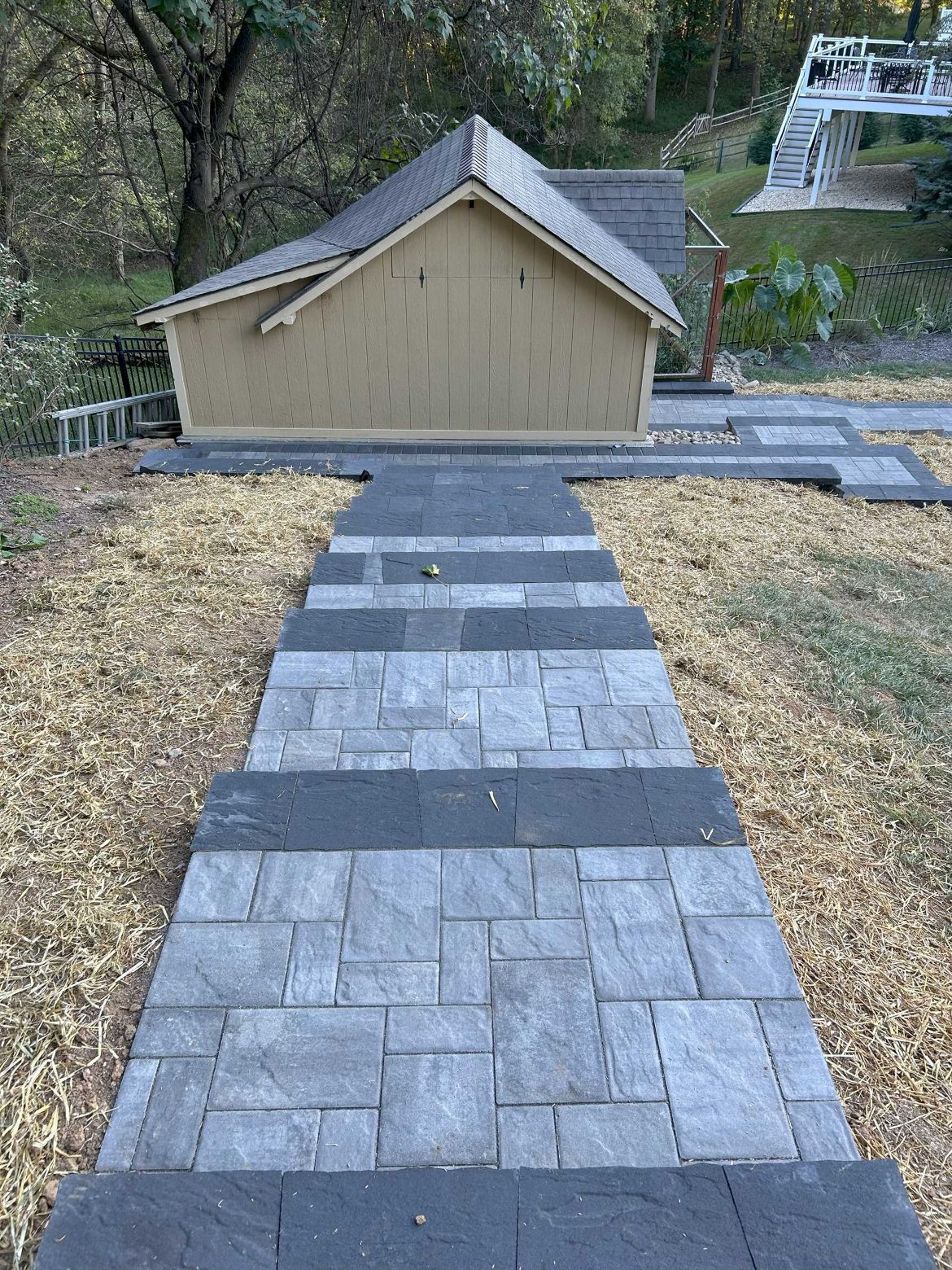 Stone steps lead up to a small building with a brown roof. Dry grass surrounds the path.