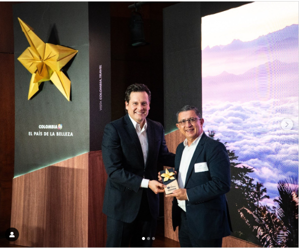 Two men in suits hold a gold star award in a lobby display