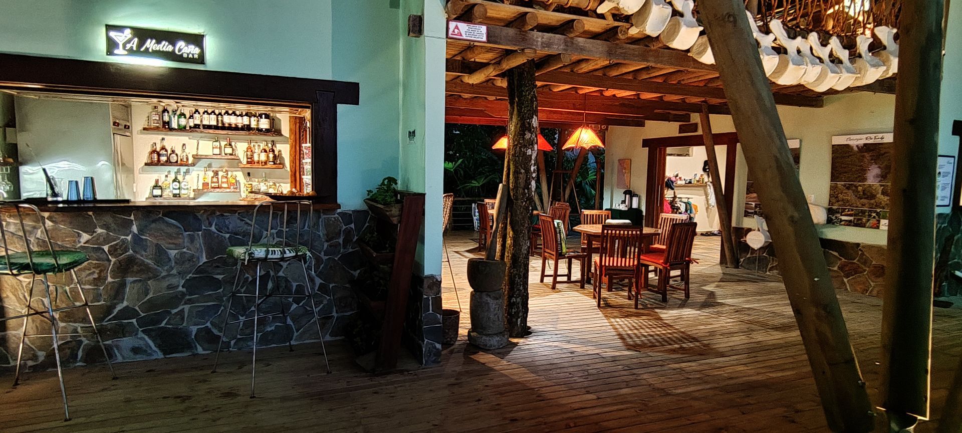 Rustic restaurant interior with stone bar, warm lights, and tables on a cobblestone floor