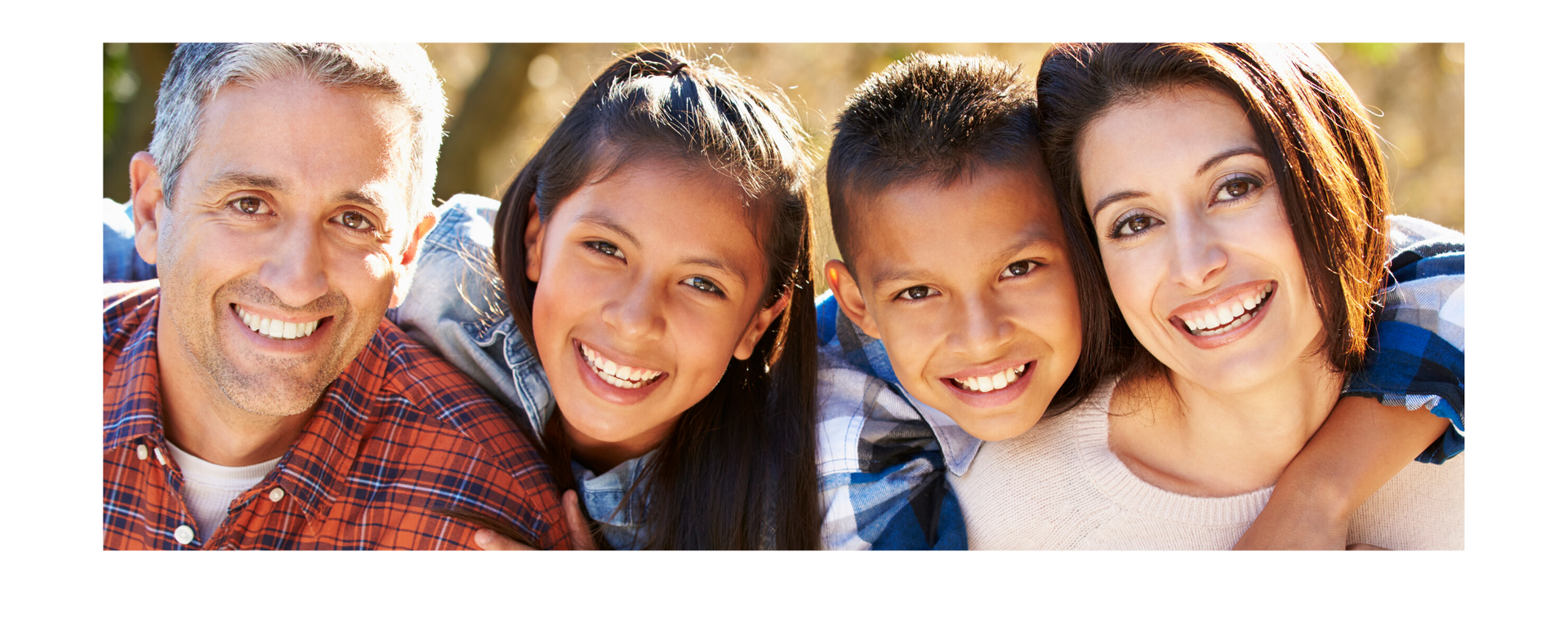 Four smiling people leaning close together in a bright outdoor portrait