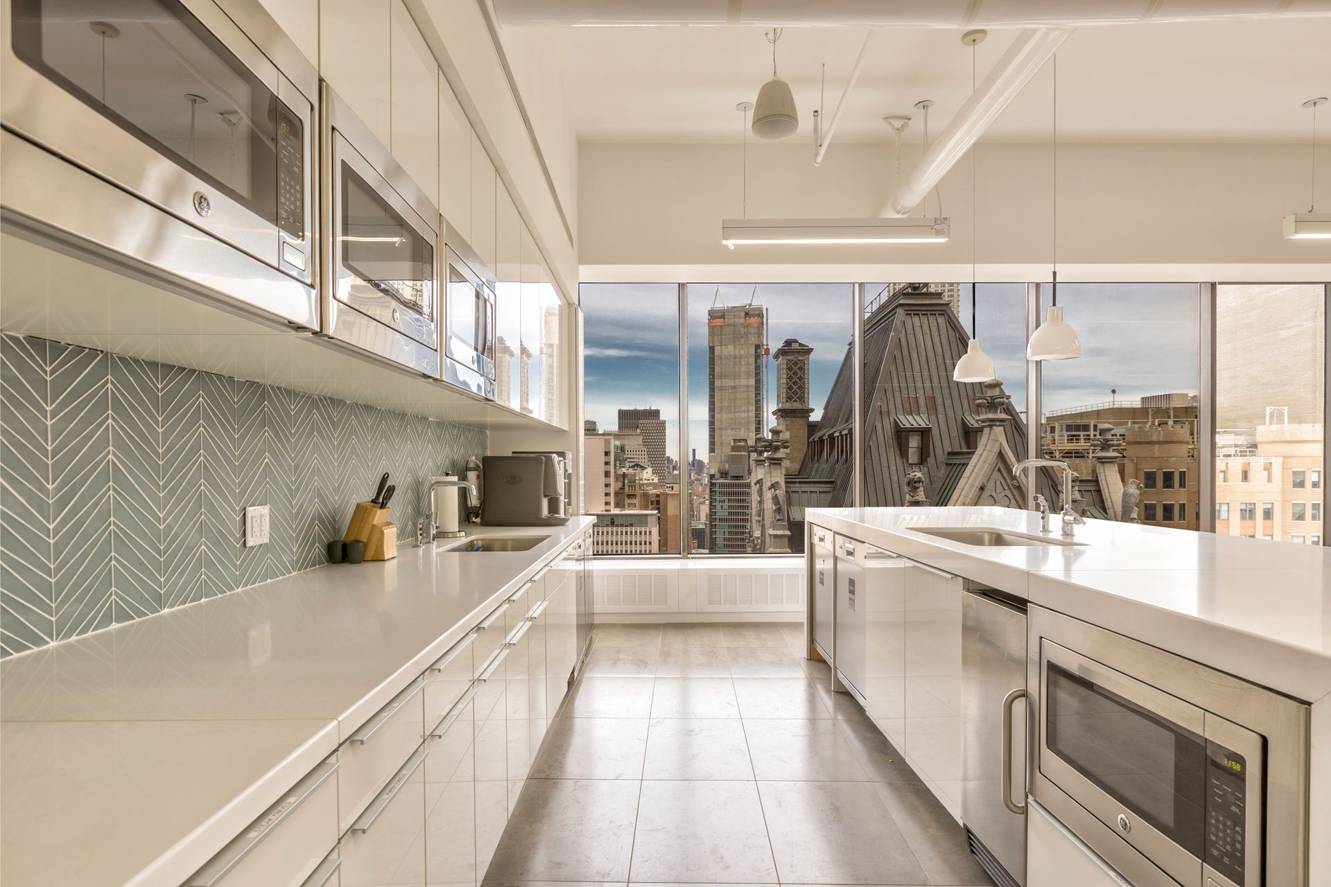 Modern kitchen with white cabinets, stainless steel appliances, and a city view.