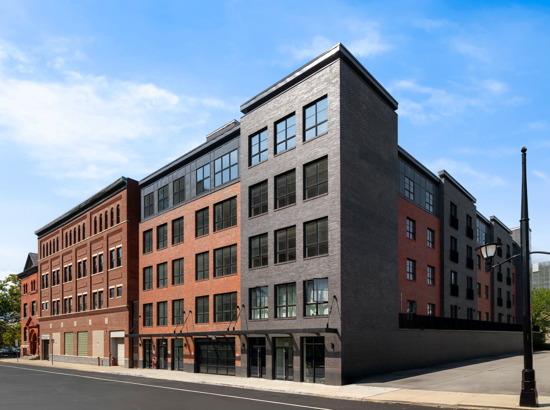 Multi-story brick building with dark gray, red, and brown facades on a sunny day.