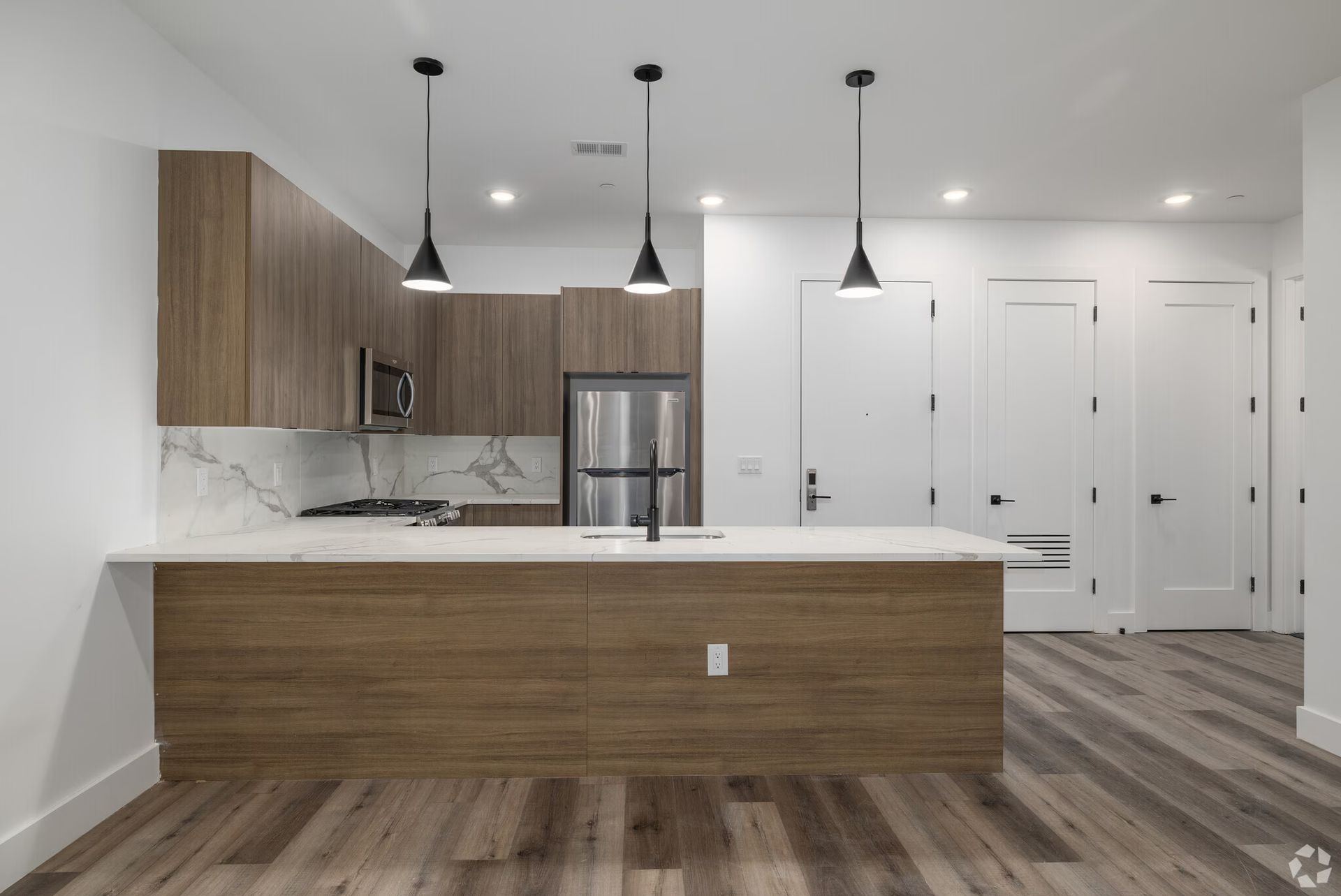 Modern kitchen with wood cabinets, island, and stainless steel appliances.