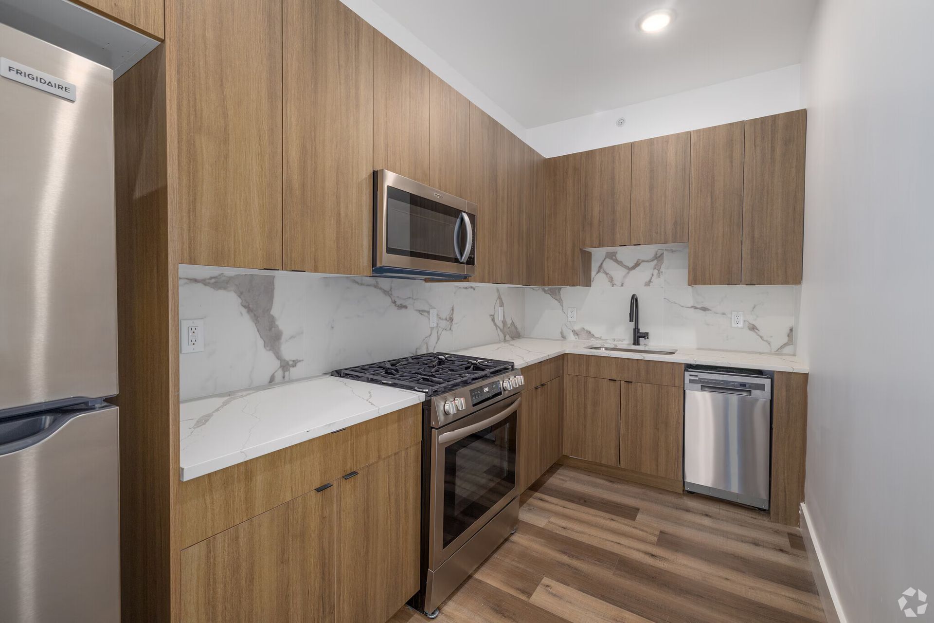 Modern kitchen with wooden cabinets, stainless steel appliances, and marble backsplash.