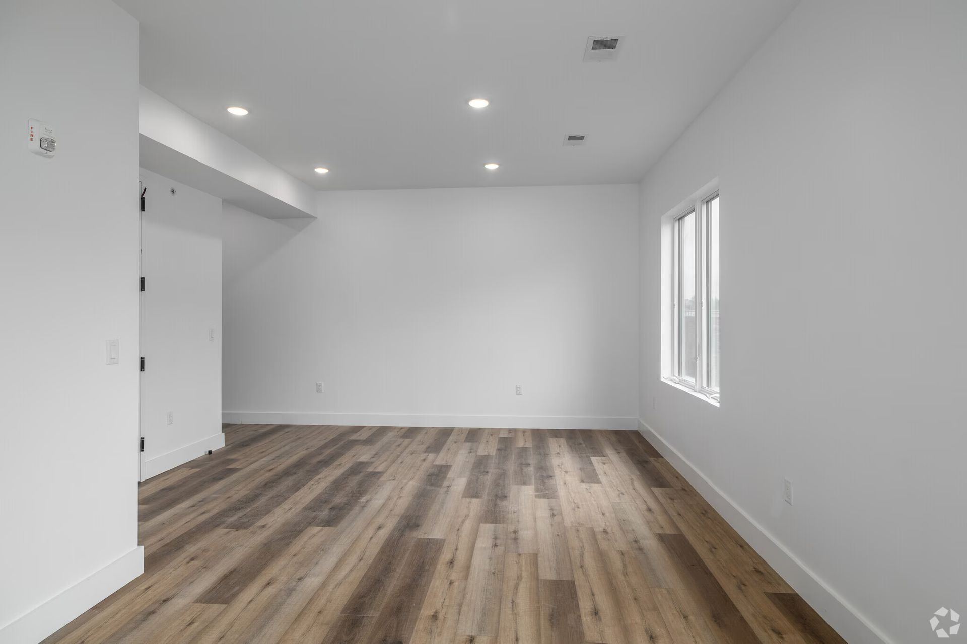 Empty room with wood floors, white walls, and a window.