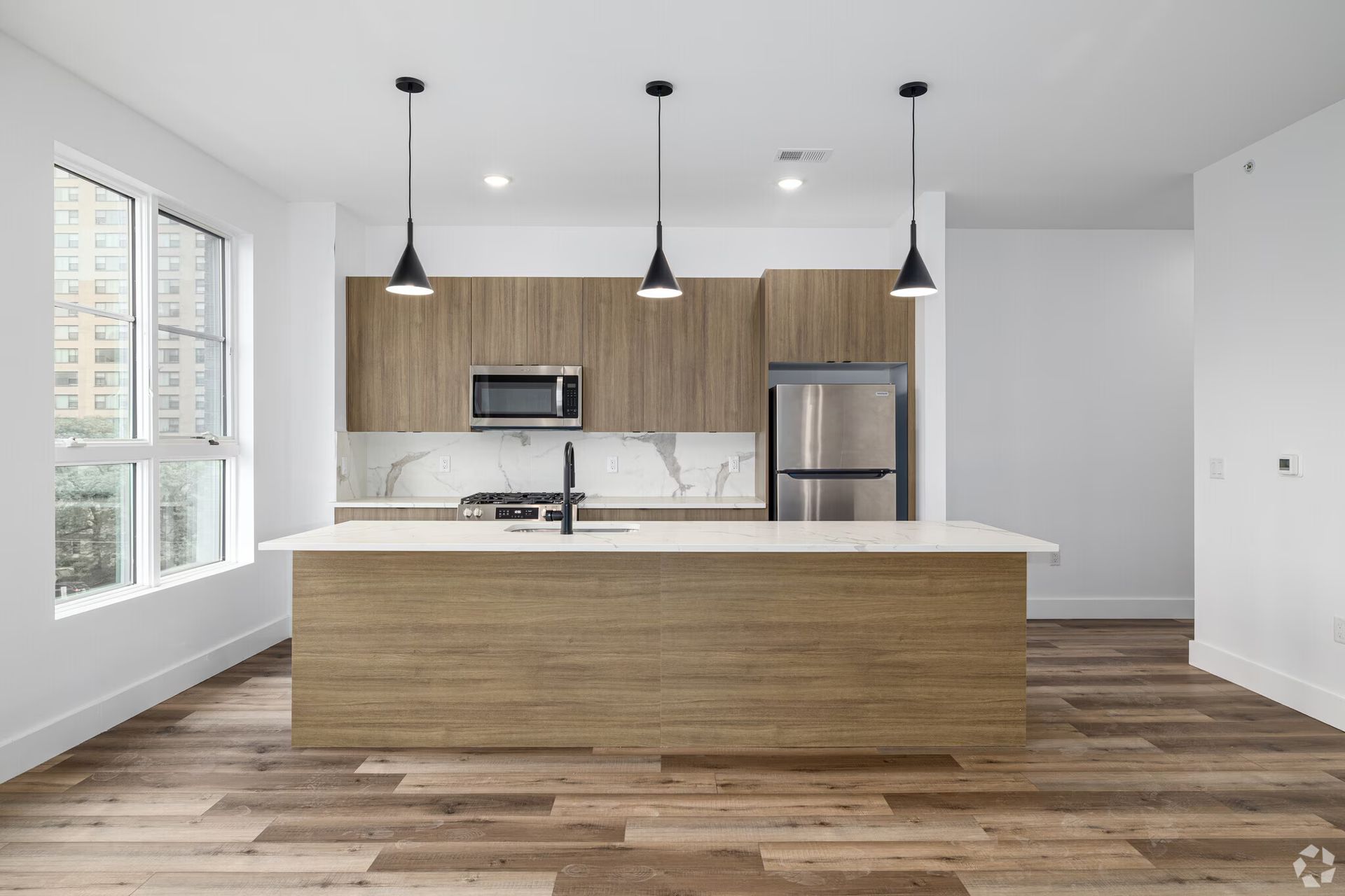 Modern kitchen with wood cabinets, island, and stainless steel appliances.