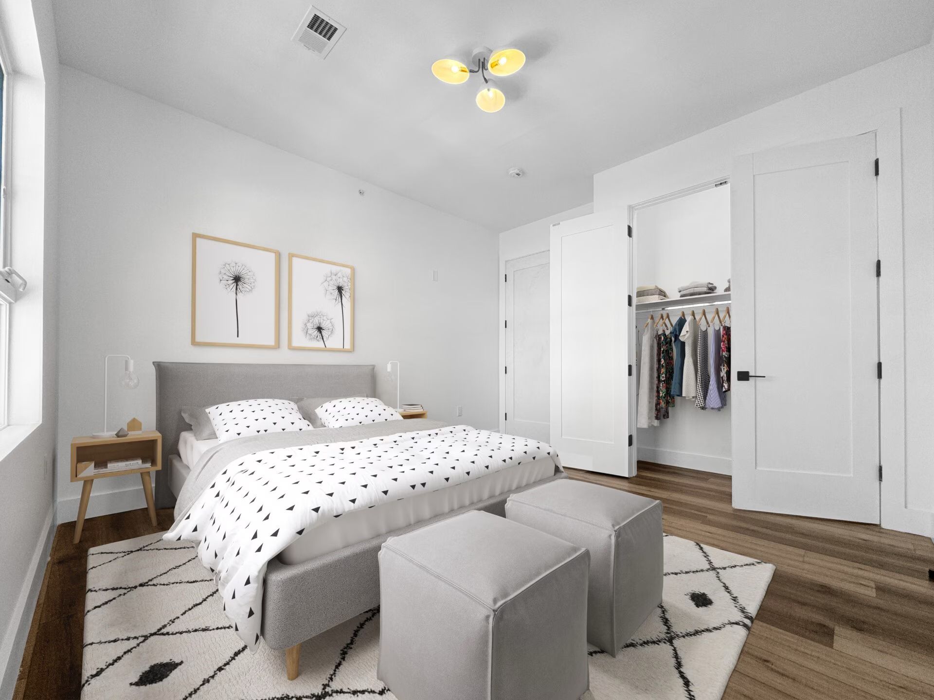 Bedroom with bed, closet, and ottomans on a patterned rug.