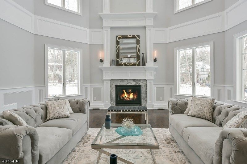 Living room with gray tufted sofas, fireplace, and large windows.